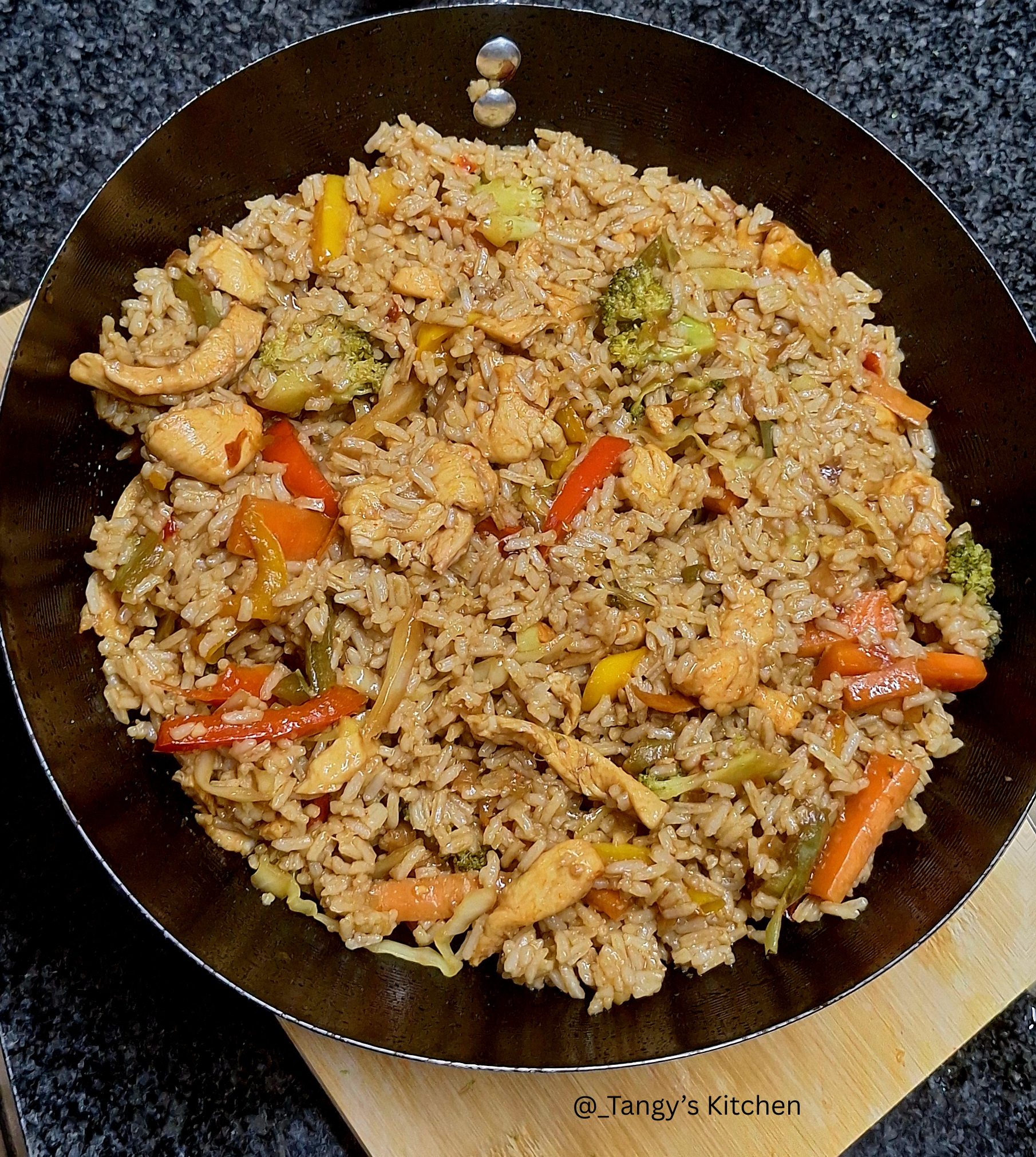 Chicken fried rice served in a white bowl, mixed with diced chicken, vegetables, and garnished with spring onions.